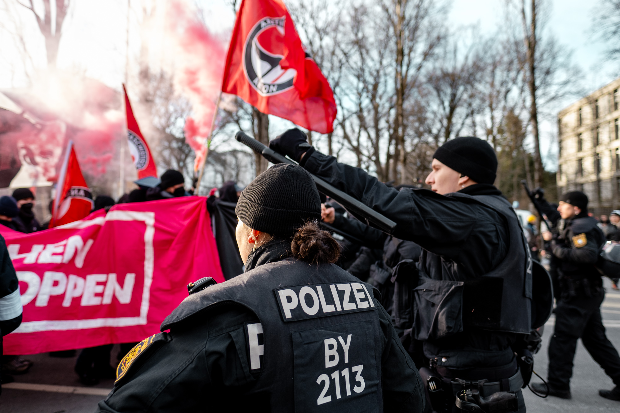 Transpi Demonstranten und rauch und Polizei mit Knüppel