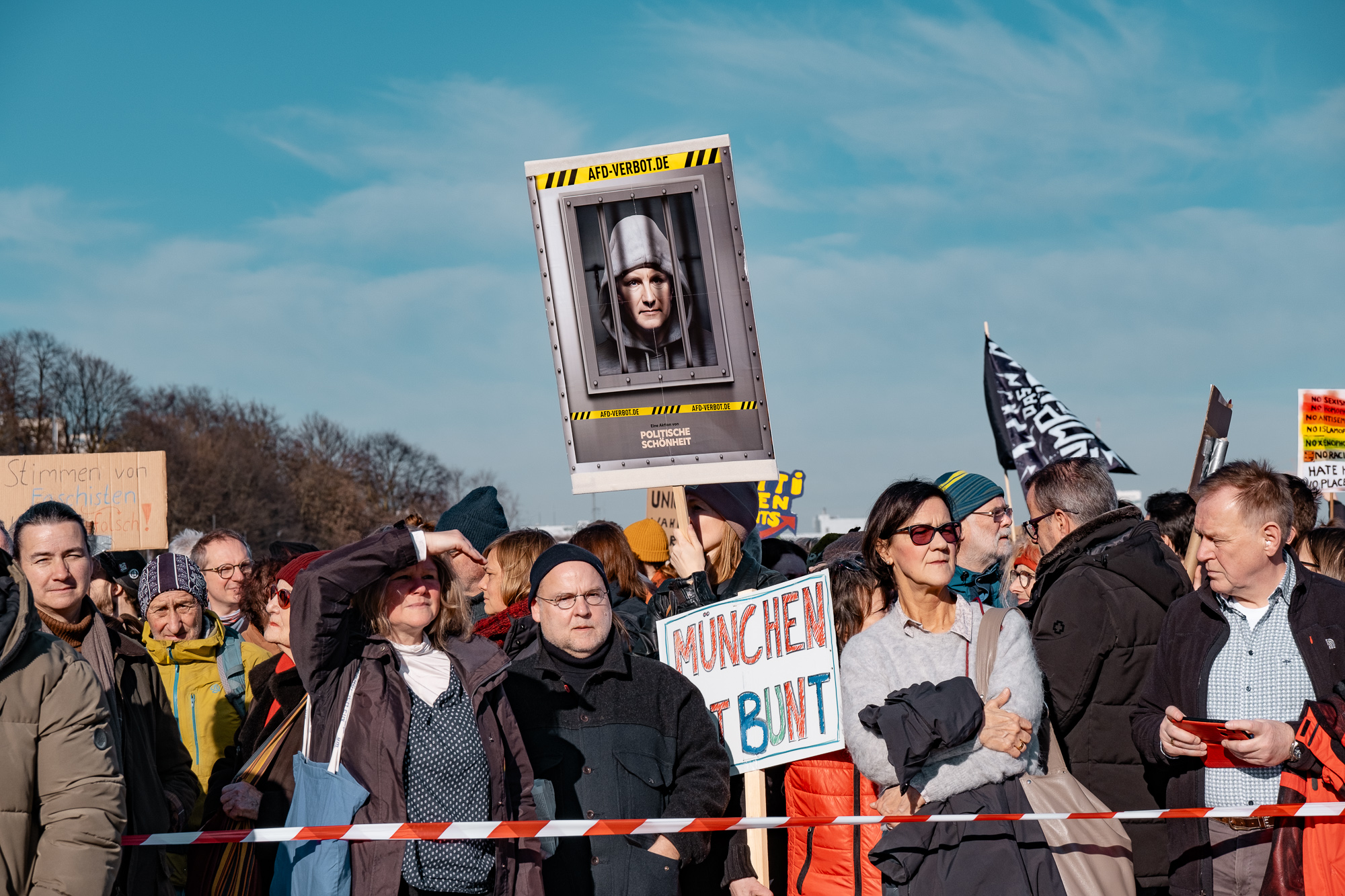 Menschen an einer Absperrung mit Schildern